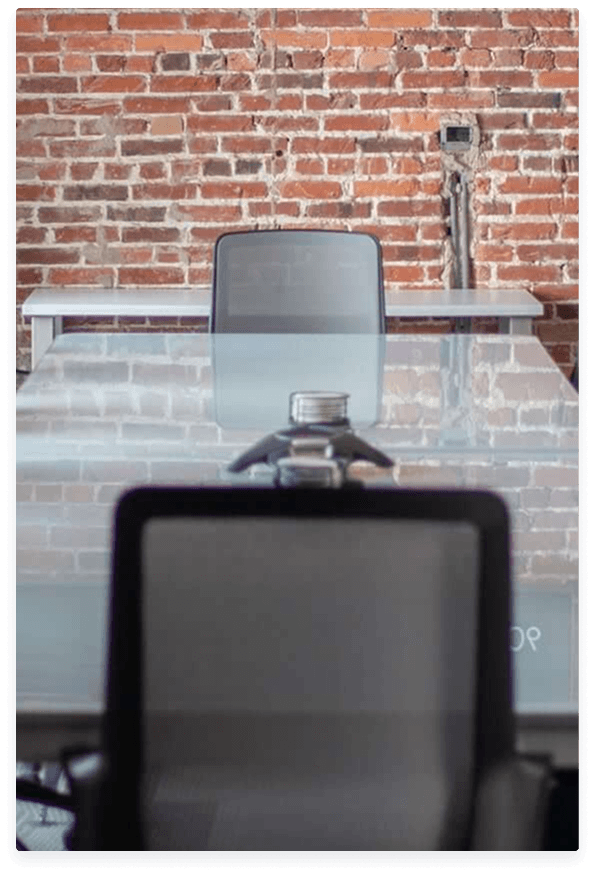 A desk and chair against a brick wall in the Launch That office