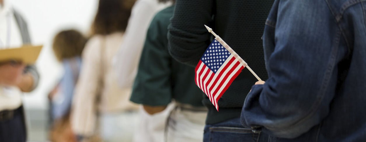 Citizen standing in line to vote carrying a small American flag